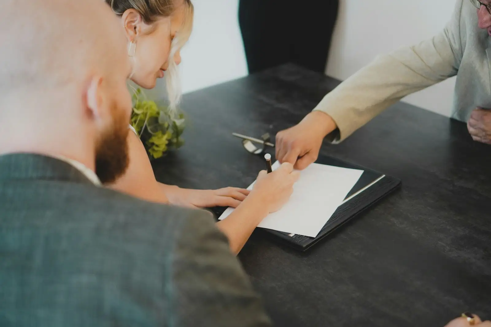 Dos personas firman un documento sobre un escritorio.