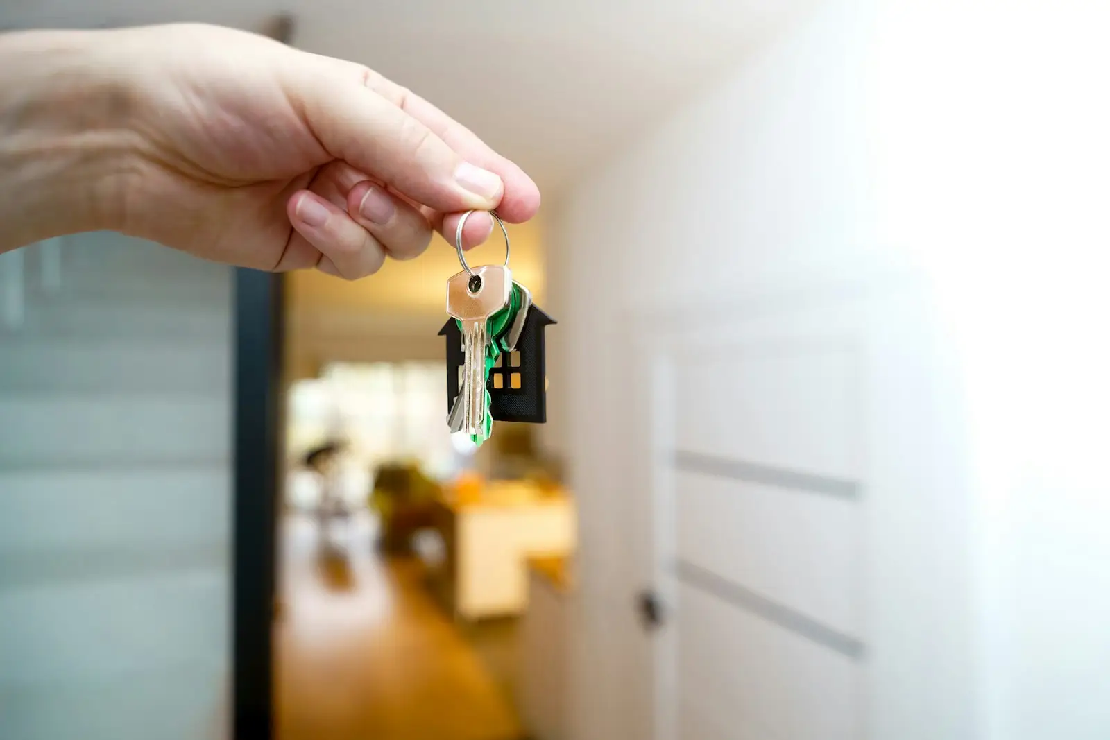 Una persona sostiene las llaves de una casa frente a la entrada.